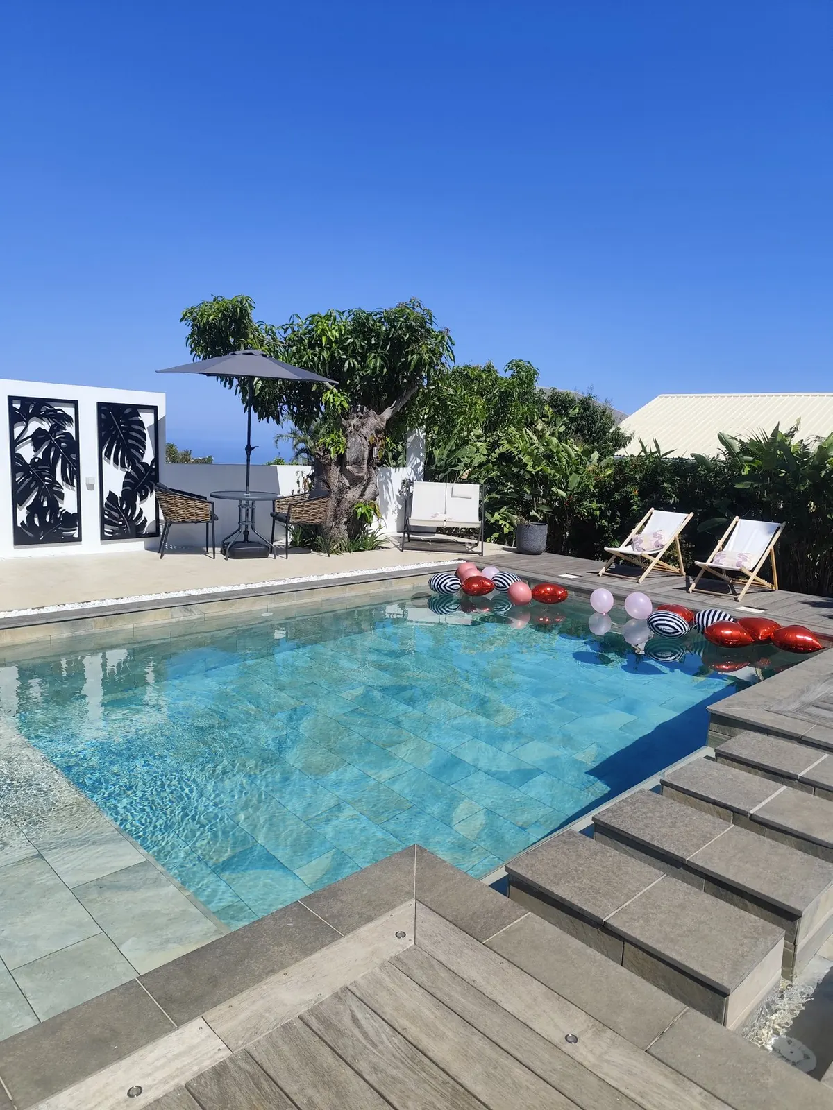 La piscine du jardin, entourée de végétation et de transats à Saint-Pierre